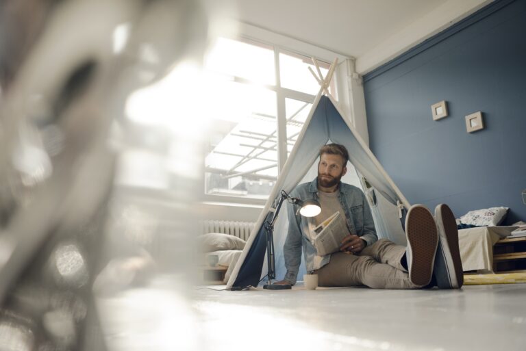 Homme campant dans son salon, lisant le journal