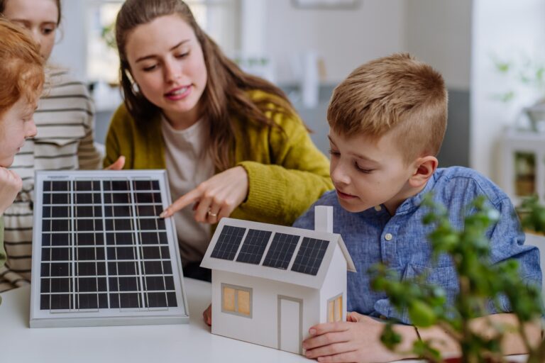 Jeune enseignante avec panneau solaire apprenant à ses élèves l'énergie solaire.