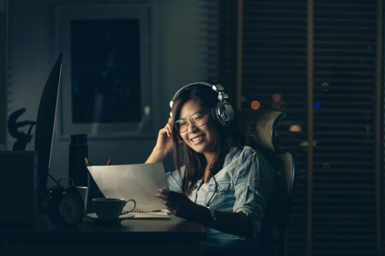 Portrait d'une femme d'affaires asiatique assise et travaillant dur avec une action de bonheur sur la table avec devant un ordinateur de bureau sur le lieu de travail à un moment tardif, concept Travailler dur et trop tard