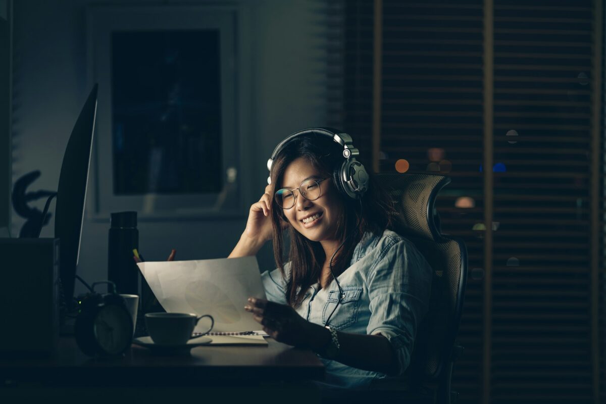 Portrait d'une femme d'affaires asiatique assise et travaillant dur avec une action de bonheur sur la table avec devant un ordinateur de bureau sur le lieu de travail à un moment tardif, concept Travailler dur et trop tard