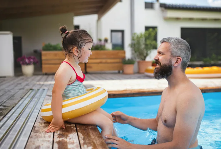 Père avec une fille heureuse à l'extérieur dans la cour, jouant dans la piscine.