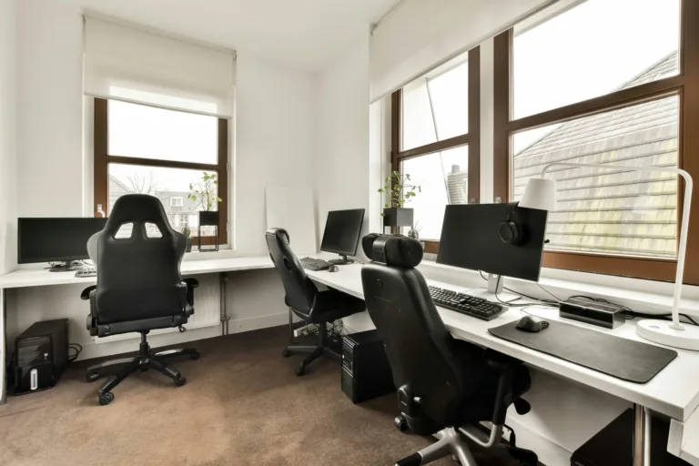 Salle informatique avec trois postes de travail et appareils modernes dans une maison confortable